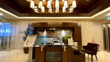 A reception desk with a 'Health Club' sign, a menu board, and a potted plant.