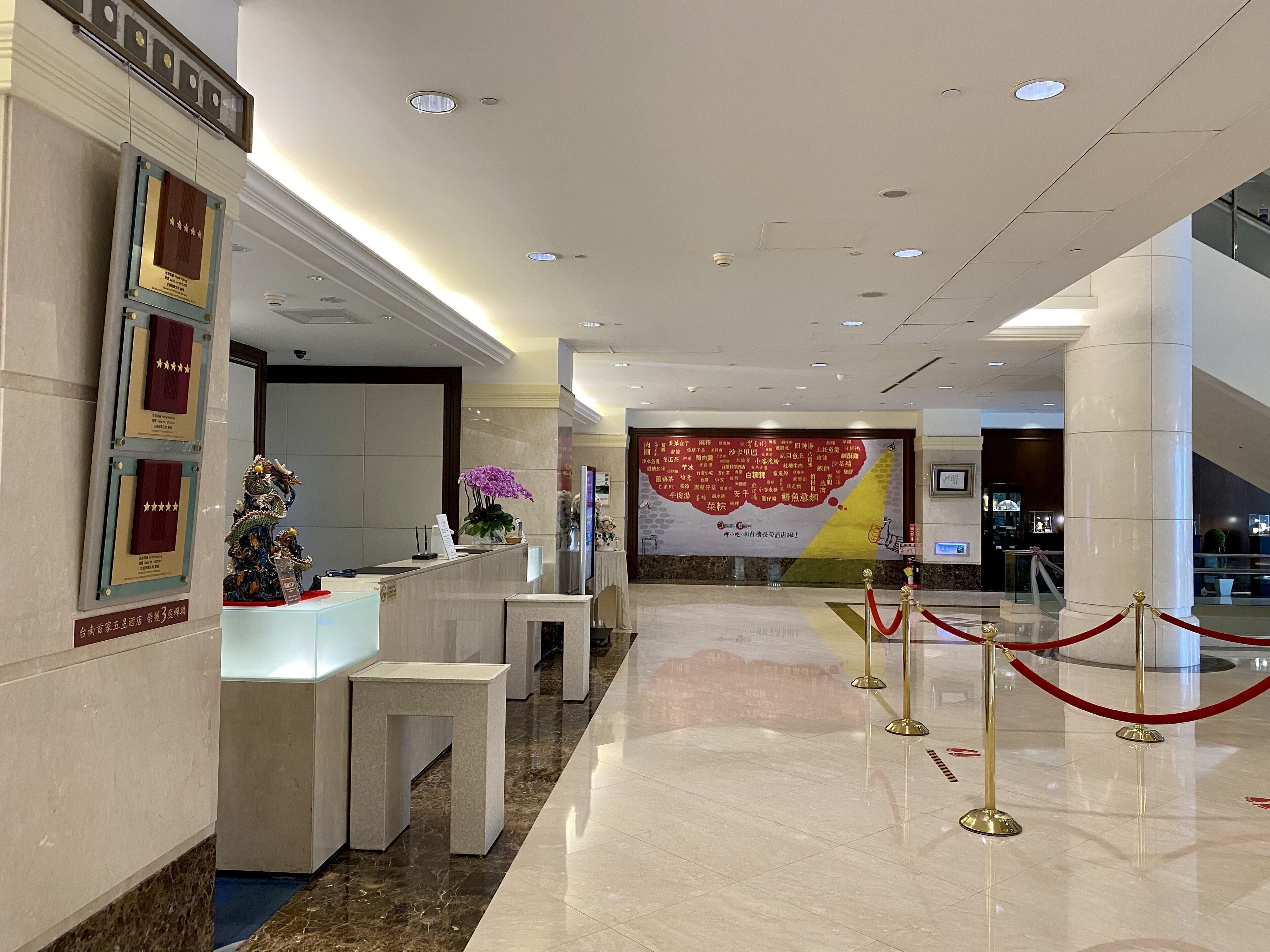 A hotel reception area with a marble floor, reception desk, and a large wall with a map and text.