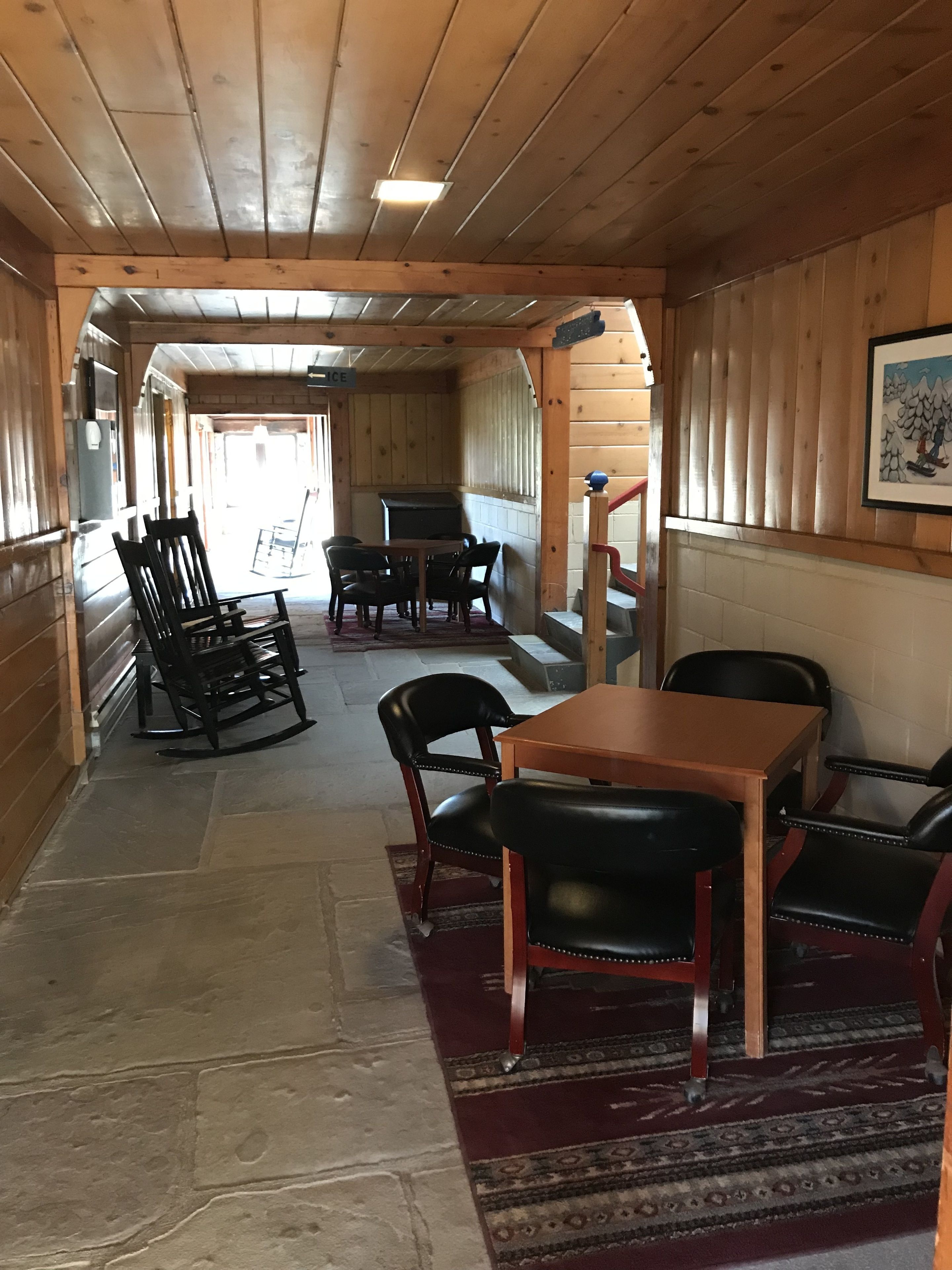 Un interno in legno con zona pranzo, tavolo, sedie, camino e una scala.