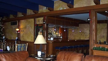 Zona de bar con un árbol de Navidad, asientos de cuero y una barra con botellas.
