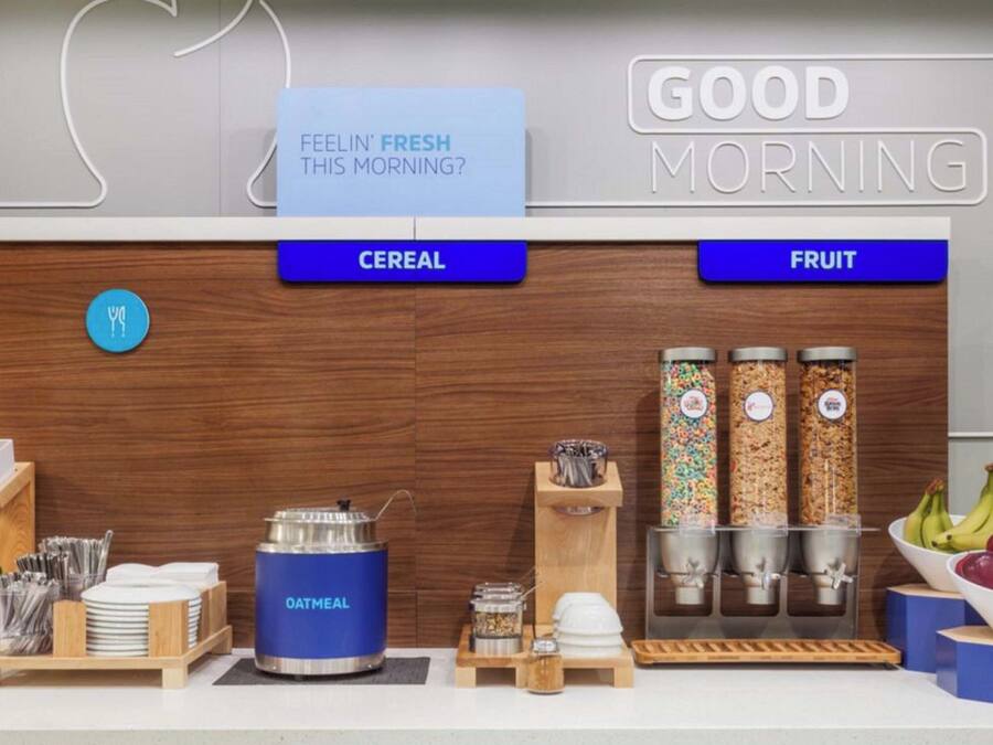 A breakfast bar with labeled sections for cereal and fruit, a kettle, and condiments.