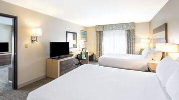 Une chambre d’hôtel avec deux lits, un bureau avec une télévision, une chaise et une fenêtre avec des rideaux.