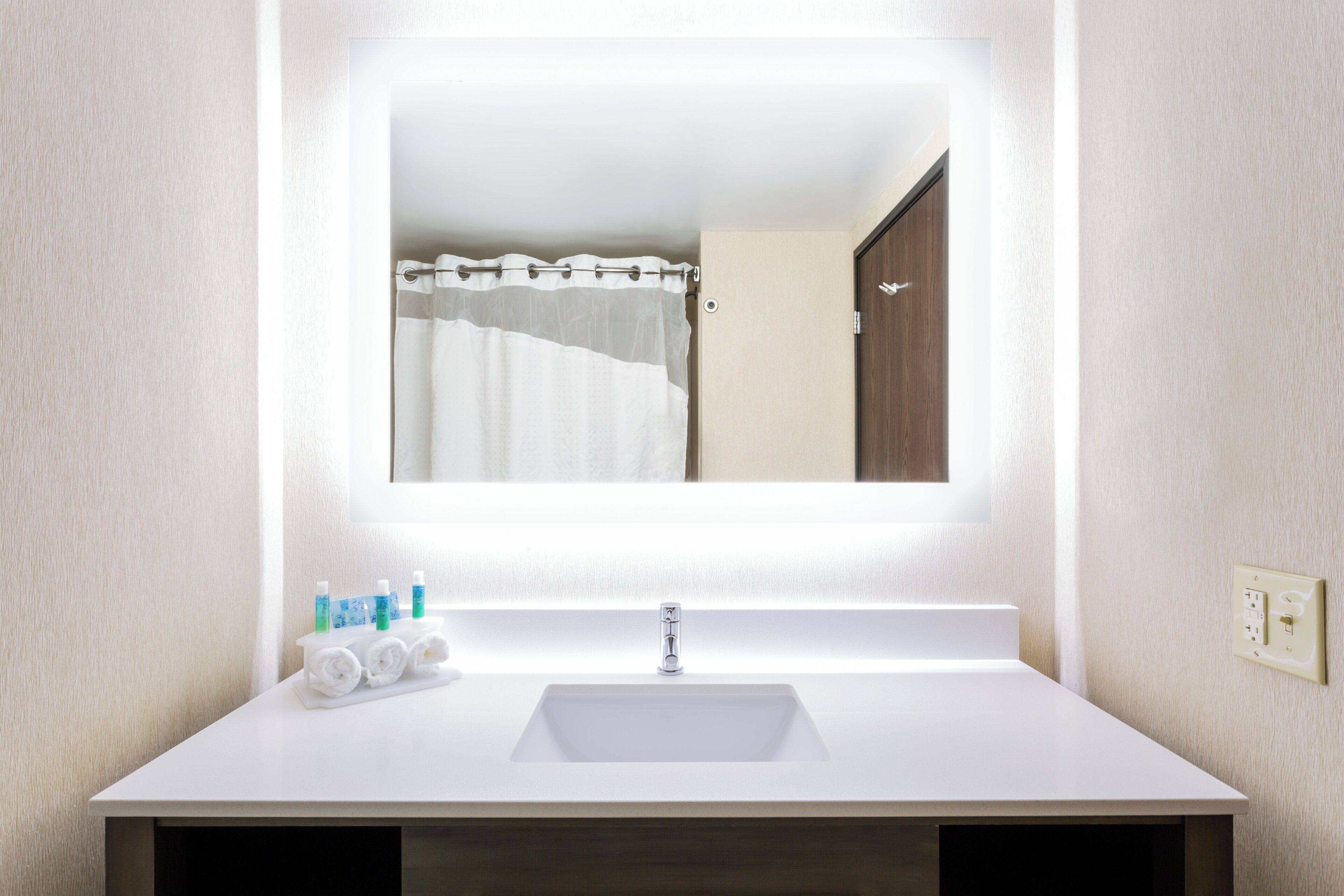 Un baño con lavamanos blanco, espejo y cortina de ducha.