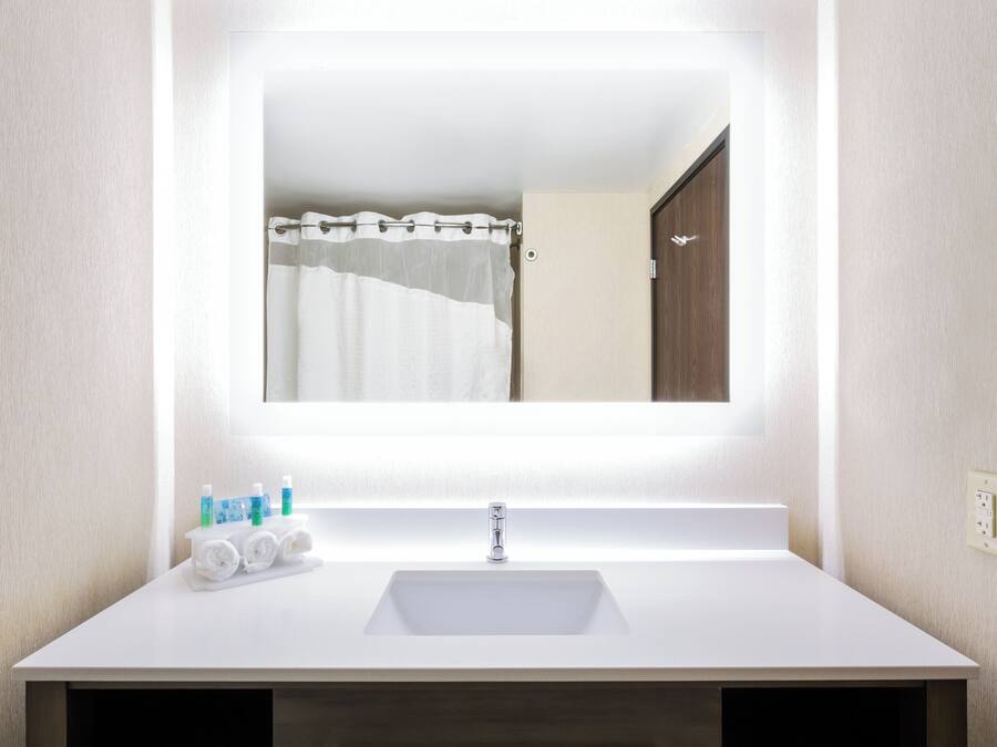 Un baño con lavamanos blanco, espejo y cortina de ducha.