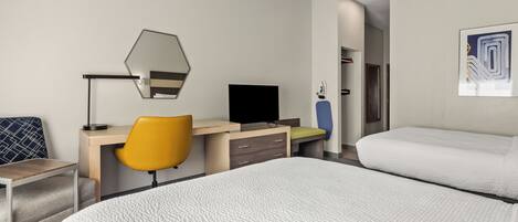 A hotel room with a bed, a desk, a chair, a TV, and a wardrobe.