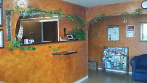 A reception area with a wooden counter, a clock, and a bulletin board with various notices. - Carefree Inn Flatonia (Flatonia)