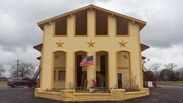 Un edificio amarillo con una bandera, ventanas arqueadas y adornos con estrellas.