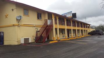 A motel with a two-story structure, a covered parking area, and a visible staircase leading to the upper level.