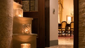 A staircase with candles, leading to a room with a wooden door and a view of a dining area. - Ca' Vendramin Zago (Venice)