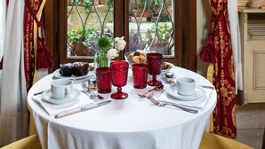 A dining table set for two with a view of a courtyard through a window with metal bars. - Ca' Vendramin Zago (Venice)