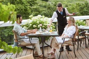 A terrace with a table set for three people, surrounded by greenery and a white railing. - Steigenberger Hotel & Spa Krems (Krems an der Donau)