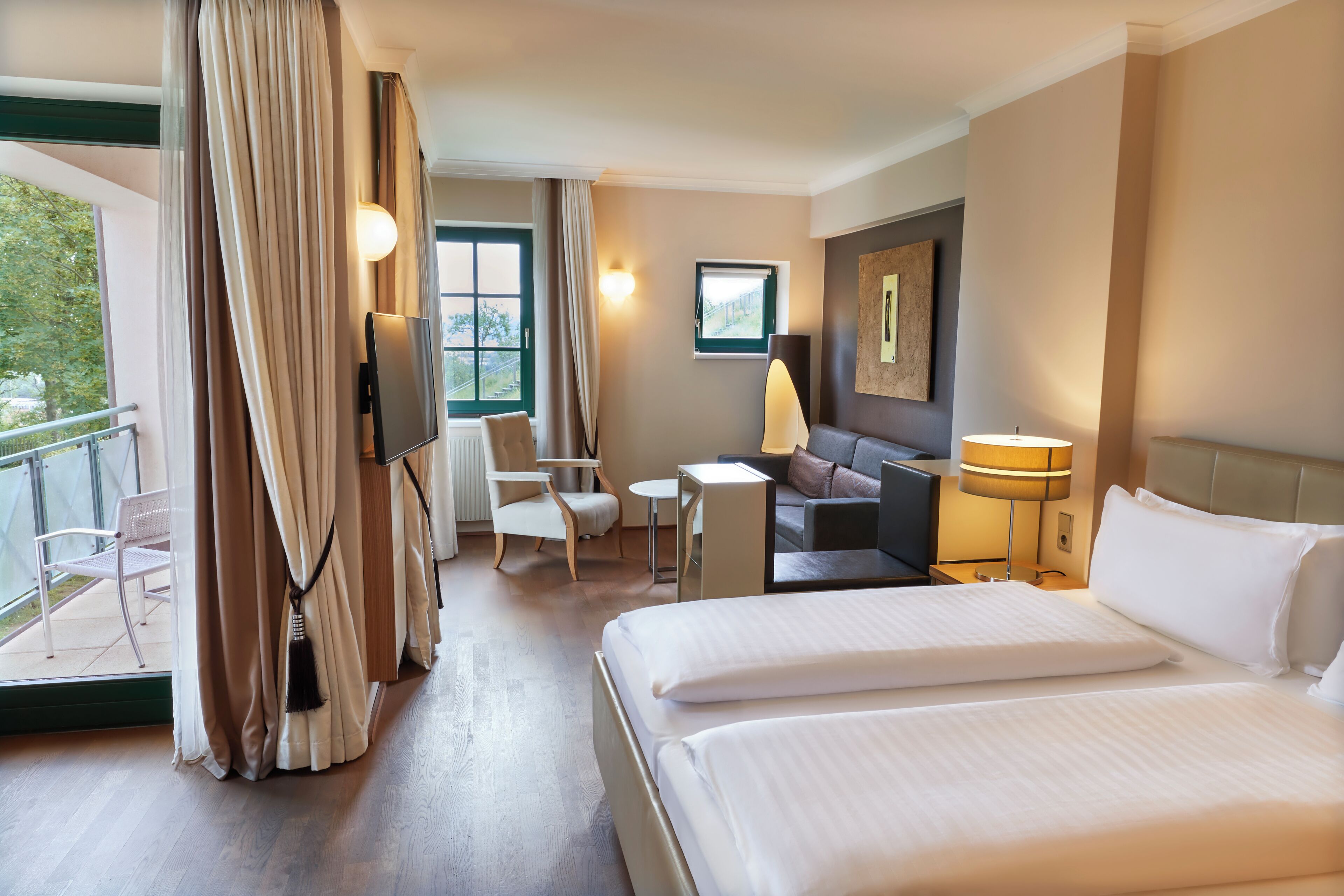 Una habitación de hotel con una cama grande, un sofá, un televisor, una mesita y una silla.