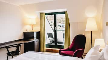 Ett hotellrum med en säng, ett skrivbord, en stol och en balkong med utsikt.