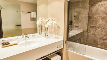 A modern bathroom with a large mirror, white sink, and a glass-enclosed shower.