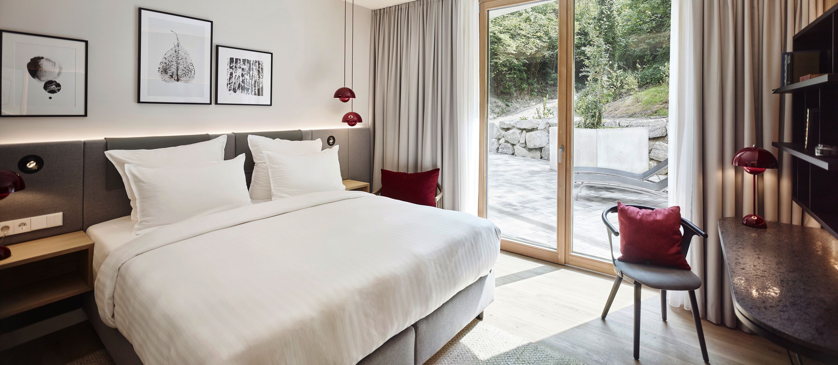 Habitación de hotel moderna con una cama grande, un escritorio, una silla y vistas al exterior.