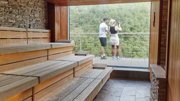 A wooden bench area with a stone wall and a balcony overlooking a forested area.