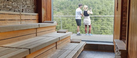 A wooden bench area with a stone wall and a balcony overlooking a forested area.