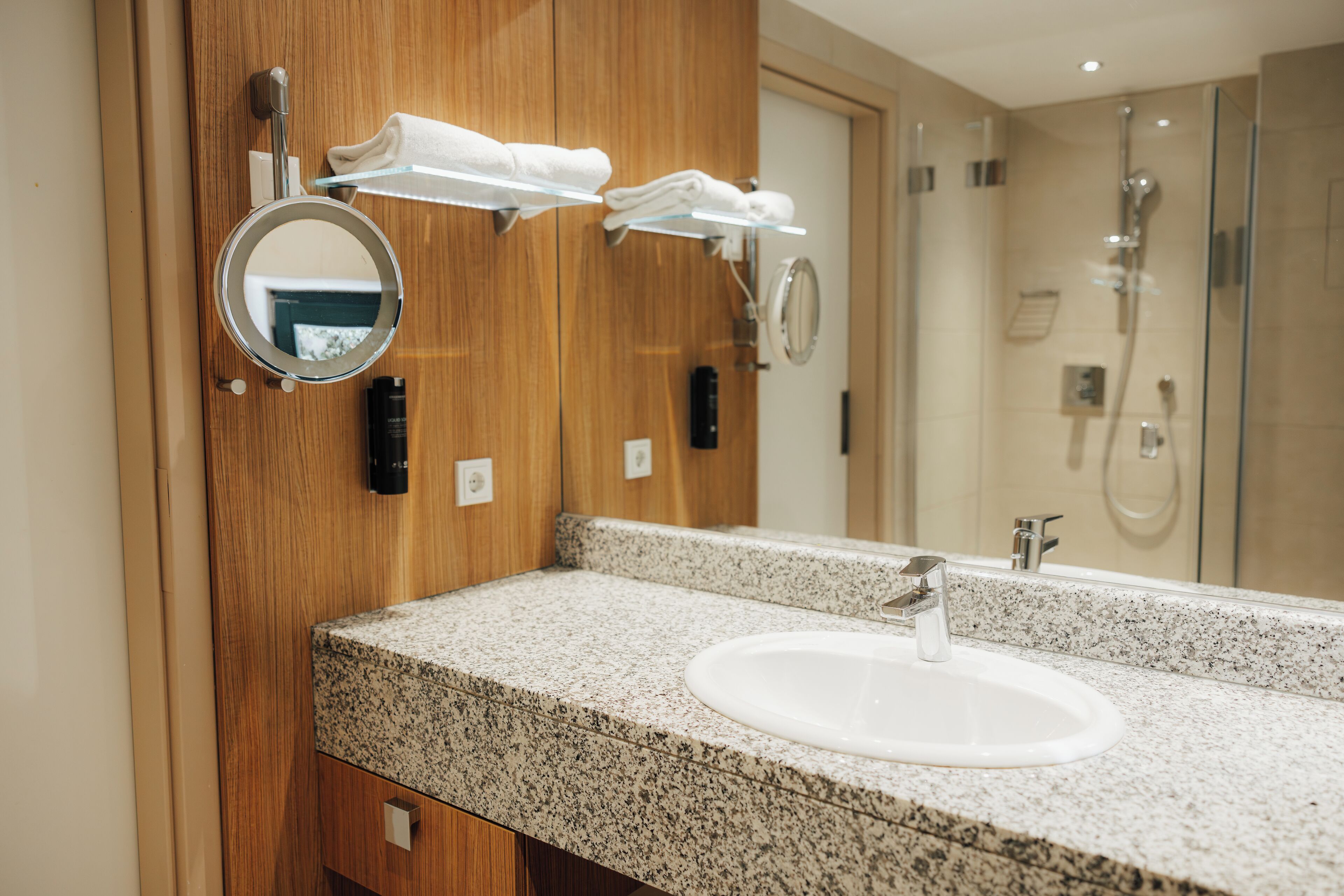 A bathroom with a granite countertop, a white sink, and a mirror.