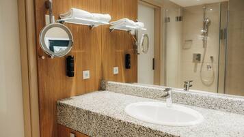 A bathroom with a granite countertop, a white sink, and a mirror.