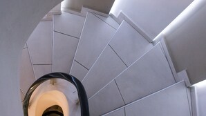 Una escalera de caracol con diseño moderno, hecha de baldosas de color claro y con barandilla.