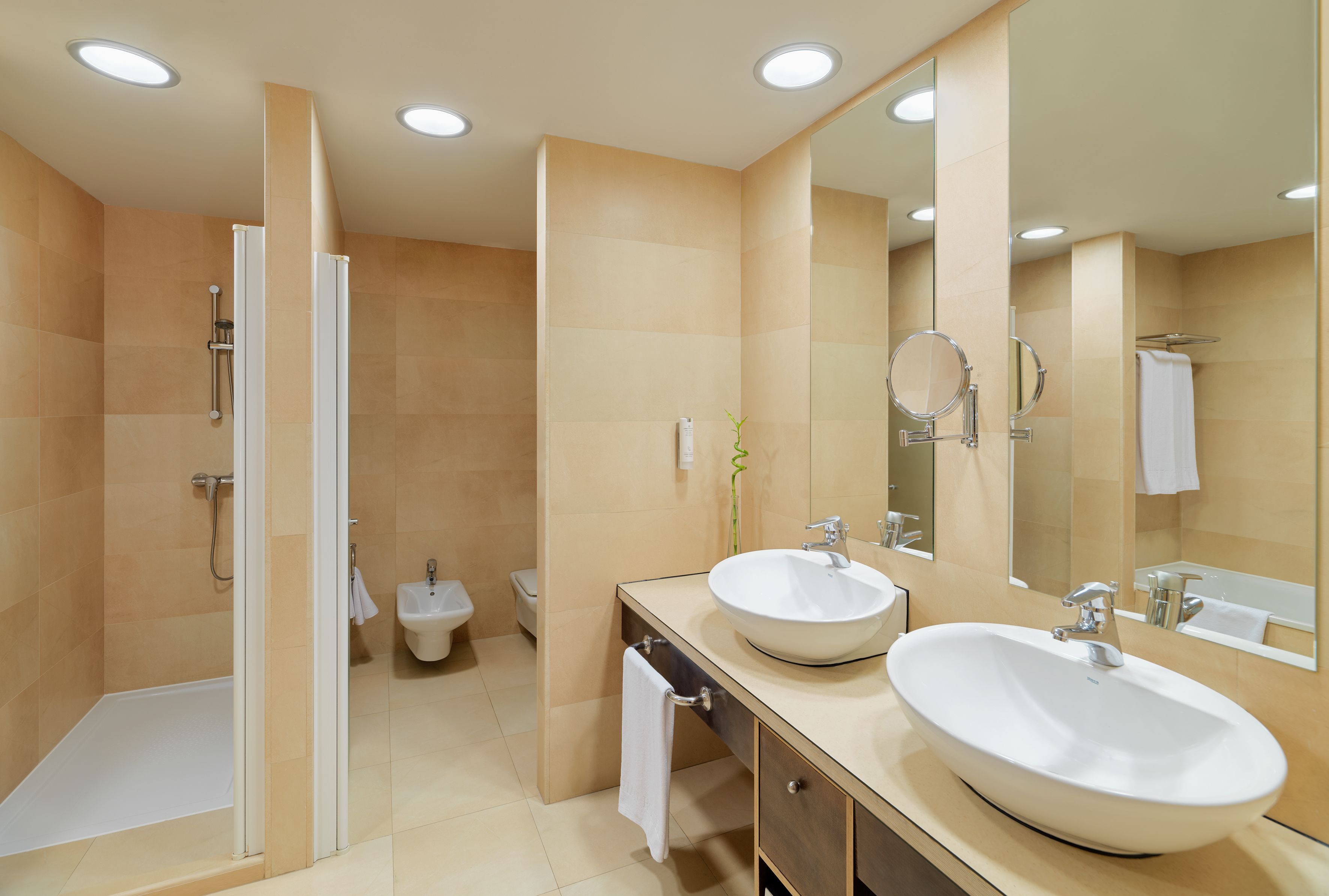 Ein modernes Badezimmer mit zwei Waschbecken, einer Dusche und einem großen Spiegel.