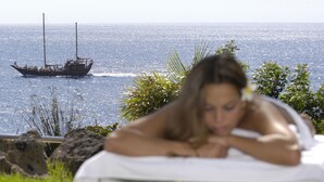 A person lying on a bed with a view of the ocean and a boat in the background. - Roca Nivaria Gran Hotel (Adeje)