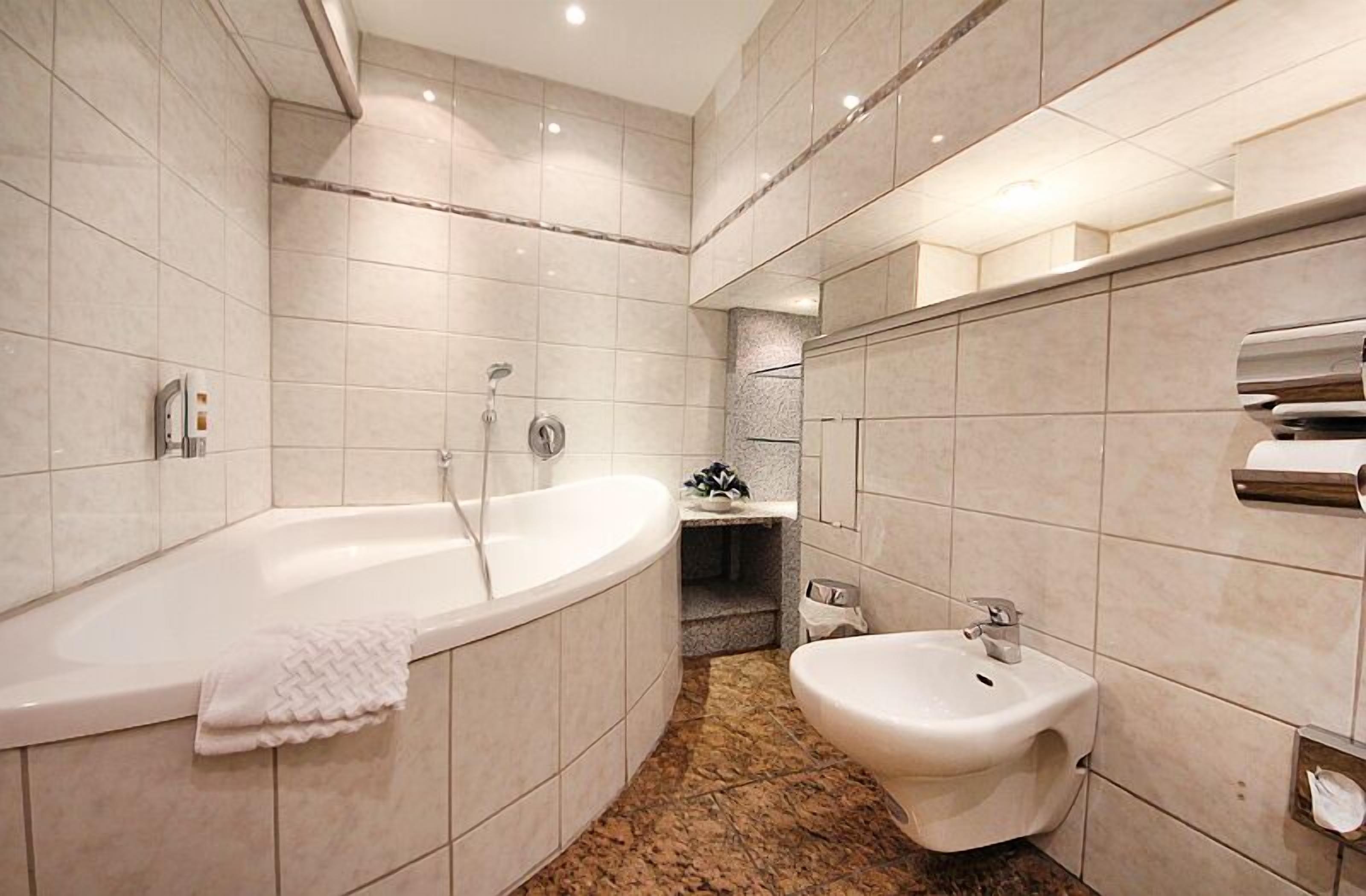 Ein modernes Badezimmer mit einer freistehenden Badewanne, einem Bidet und einem Waschtisch mit Spiegel.