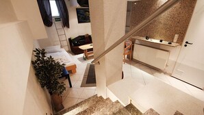 Un escalier menant à une chambre à coucher équipée d’un lit, d’une table de chevet et d’une plante en pot.