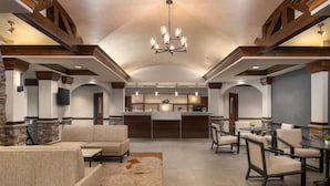A spacious lobby with a reception desk, seating area, and a chandelier.