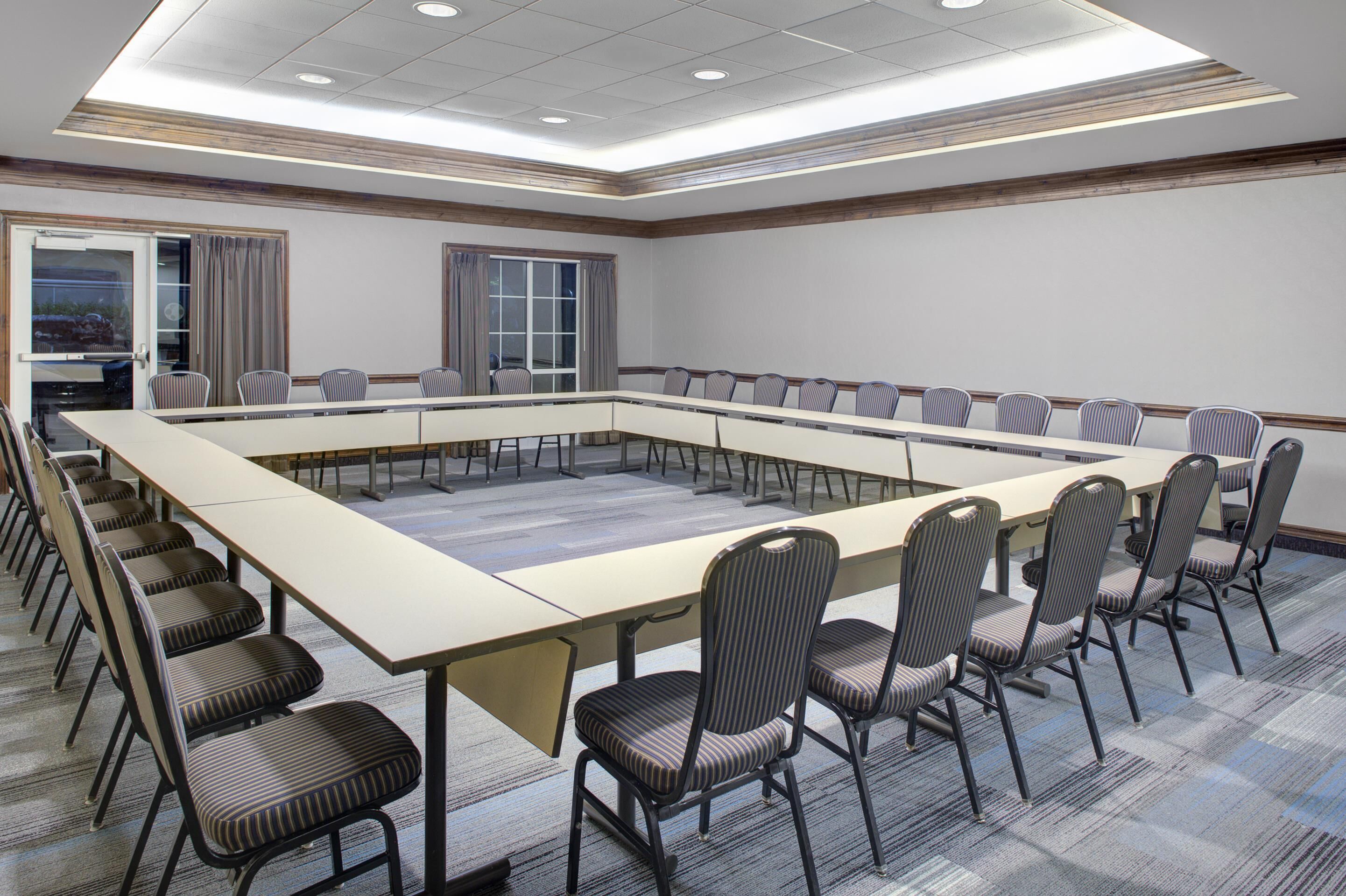 A conference room with a long table, chairs, and a carpeted floor.