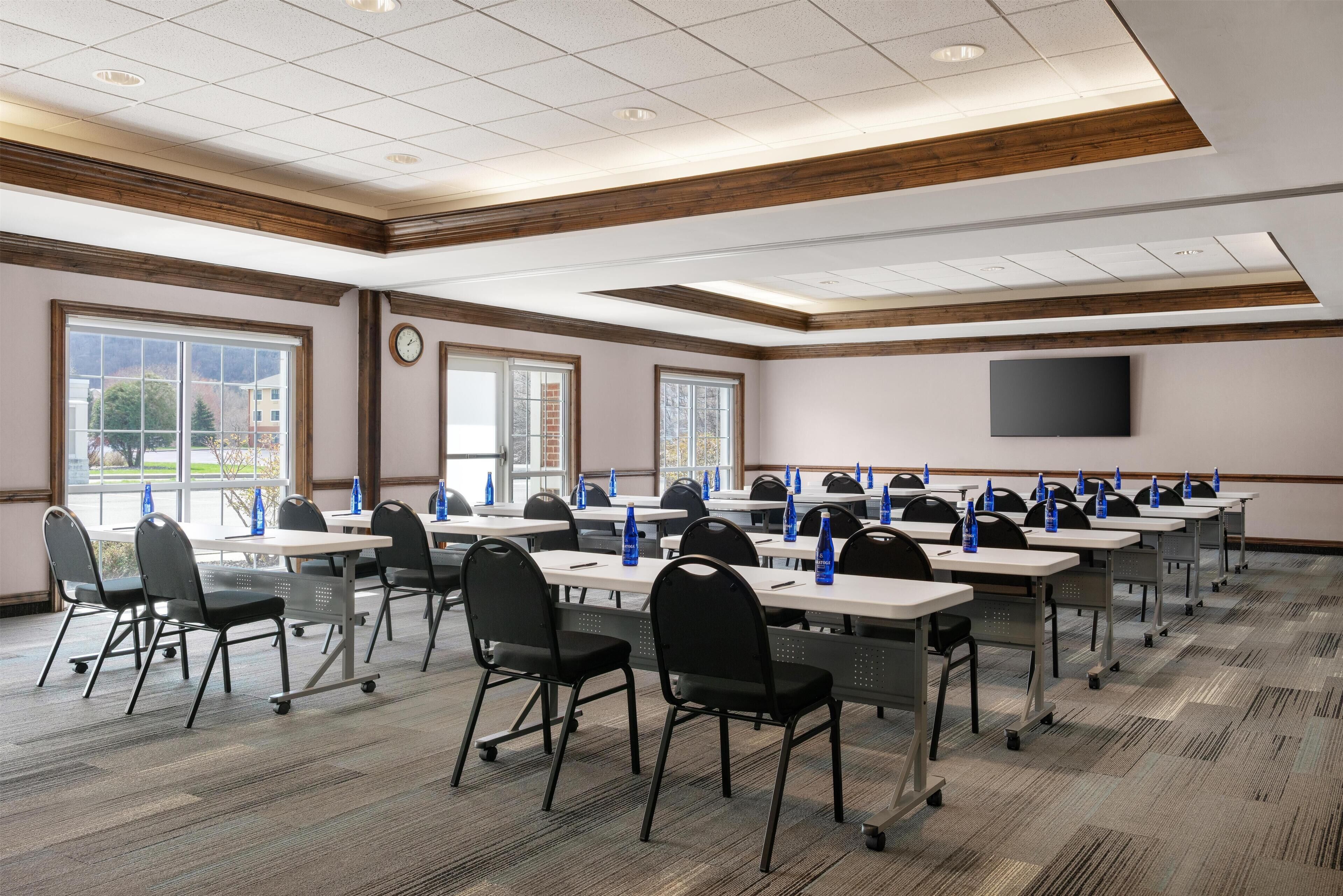 A conference room with tables, chairs, and a TV screen.