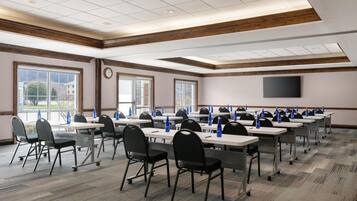A conference room with tables, chairs, and a TV screen.