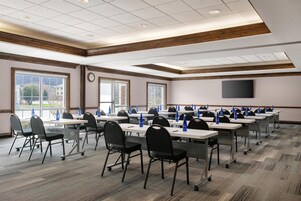 A conference room with tables, chairs, and a TV screen.
