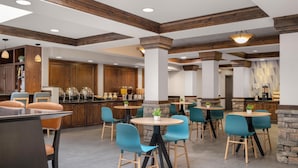 A restaurant with wooden beams, stone pillars, and teal chairs.