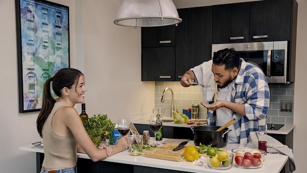 A modern kitchen with dark cabinets, a stainless steel microwave, and a white countertop.
