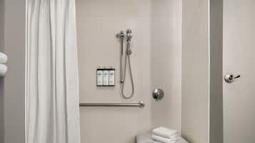 A shower area with a grab bar, a towel rack, and a small bench.