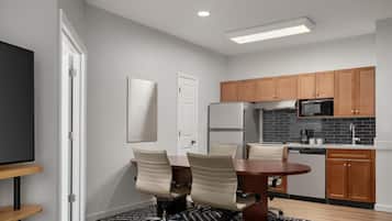 A modern kitchen with wooden cabinets, a refrigerator, microwave, and a dining area with a table and chairs.