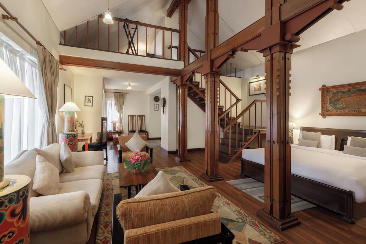 Ein geräumiges Wohnzimmer mit hoher Decke, einer Holztreppe und einem großen Bett.