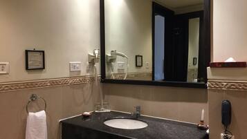 A bathroom with a black countertop sink, a mirror, a towel rack, a hairdryer, and a phone.