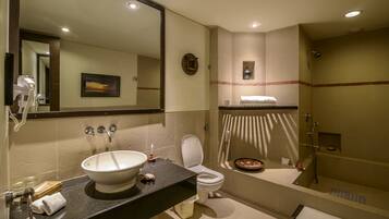 A modern bathroom with a large mirror, a sink, toilet, and a bathtub.