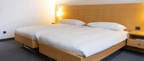Una cama doble con estructura de madera, dos mesitas de noche y una lámpara de pared.