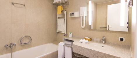 A modern bathroom with a bathtub, a sink, a mirror, and a towel rack.