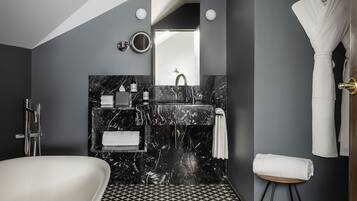 Un baño moderno con una bañera independiente, un tocador de mármol y un suelo con estampado geométrico.