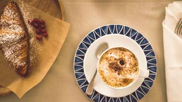 A croissant and a cup of coffee on a table with a napkin and a fork.