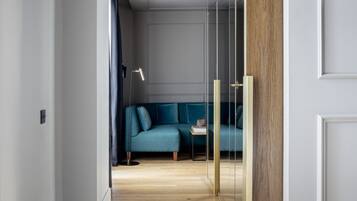 Una habitación moderna con suelo de madera, un sofá azul y un separador de vidrio.