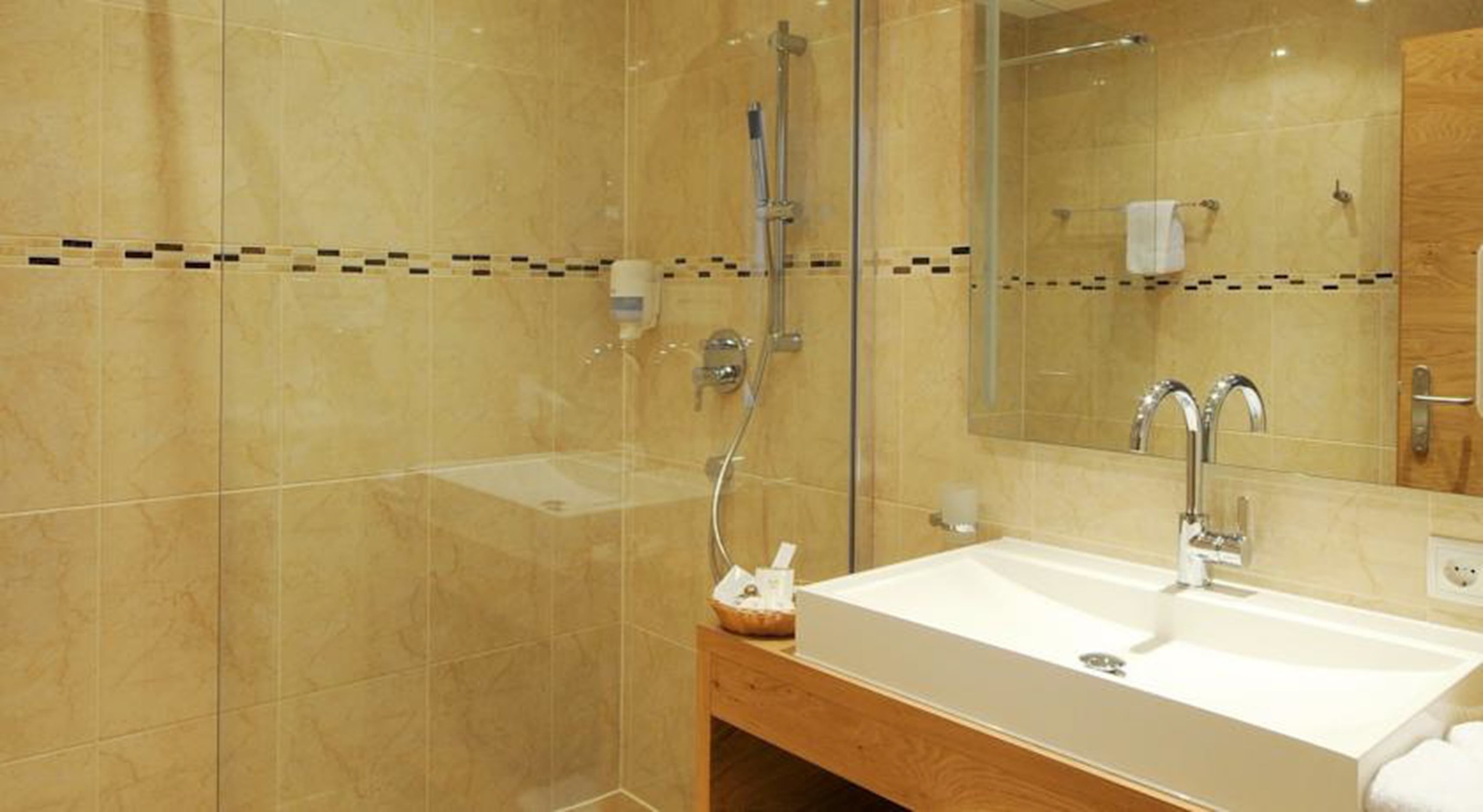 A modern bathroom with a glass shower enclosure, a white sink, and a wooden vanity.