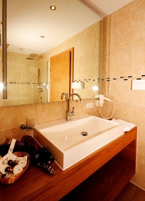 A modern bathroom with a large mirror, a wooden vanity, a white sink, and a shower area.