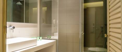Un baño moderno con cabina de ducha de vidrio, un lavabo blanco y un espejo.