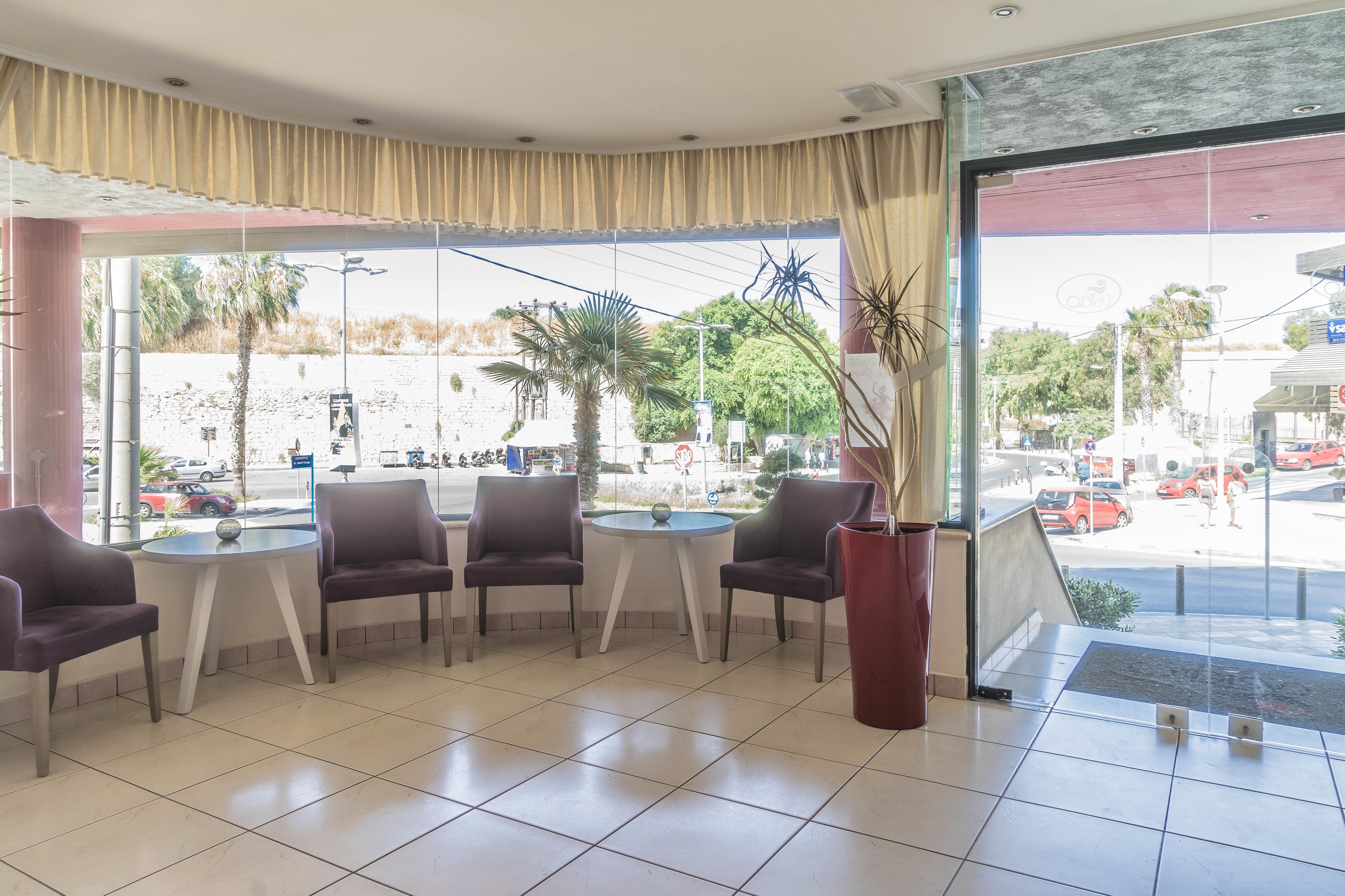 A hotel lobby with a seating area, large windows, and a view of the street outside.