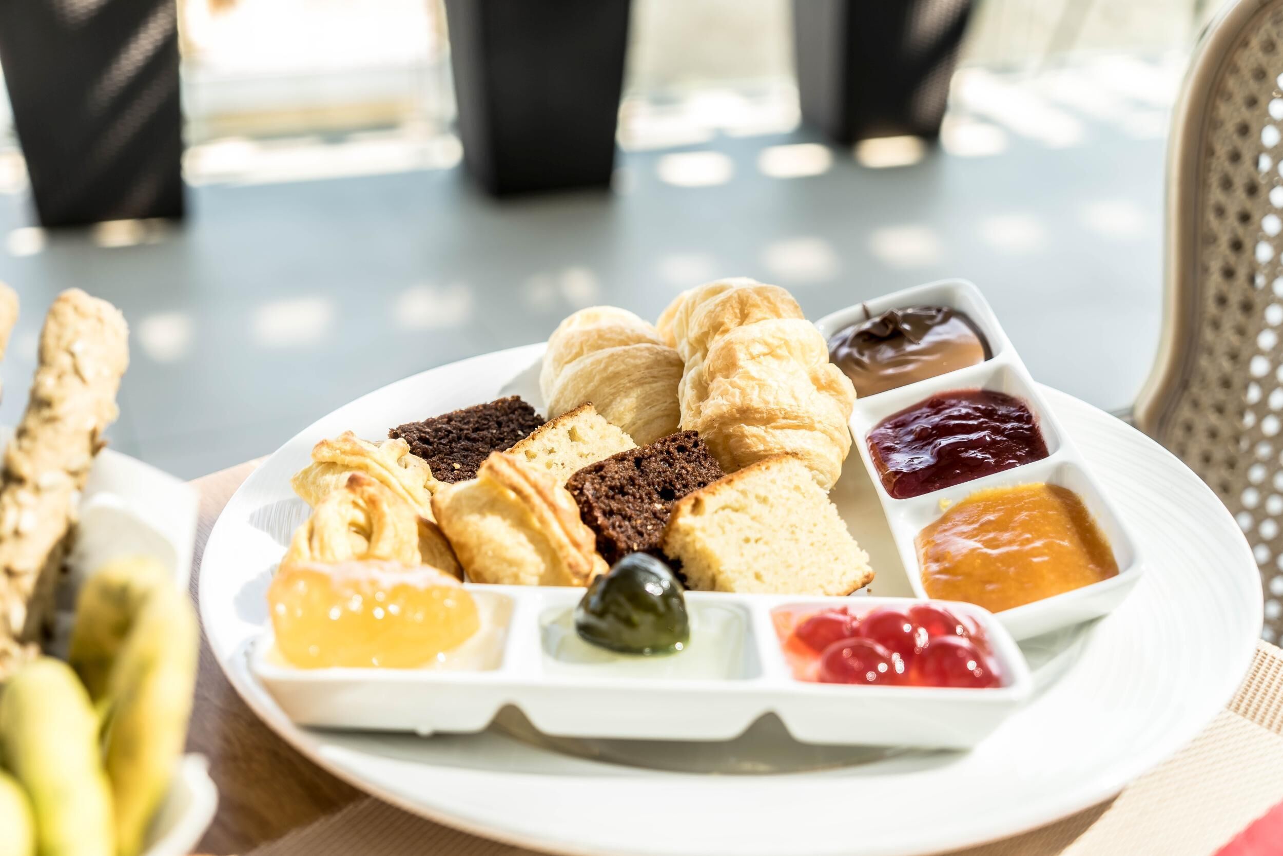 Un plato con varios pasteles y mermeladas sobre una mesa.